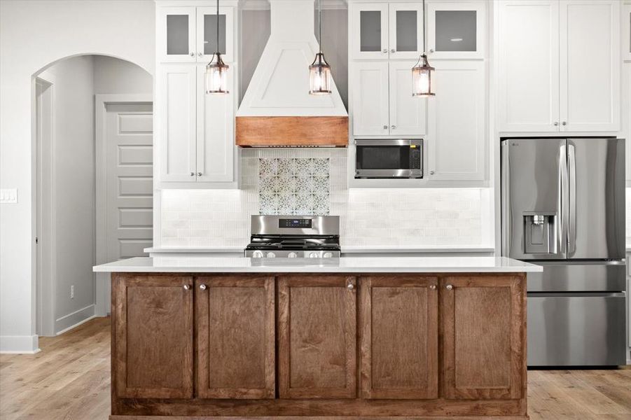 Kitchen featuring stainless steel appliances, backsplash, a kitchen island, and glass insert cabinets Kitchen featuring stainless steel appliances, backsplash, a kitchen island, and glass insert cabinets