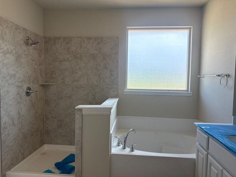 Bathroom featuring a large soaking tub, separate shower with tiled surround, and a frosted window Bathroom featuring a large soaking tub, separate shower with tiled surround, and a frosted window