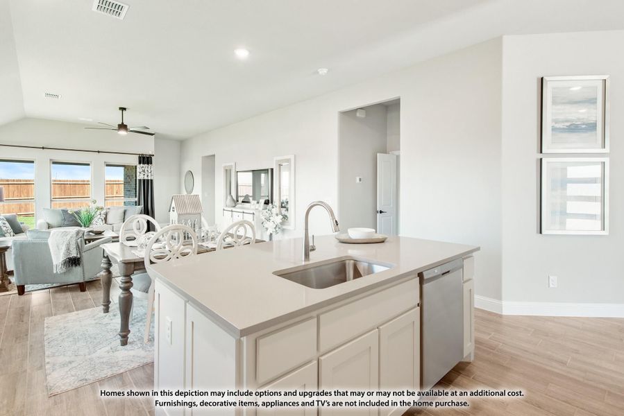 Kitchen island with sink and light countertops open to dining and living areas with hardwood floors