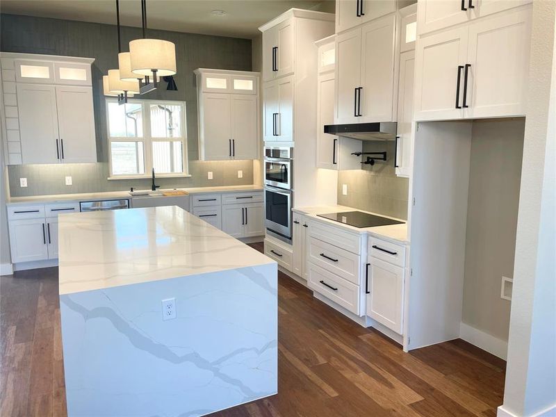 Kitchen with a center island, stainless steel appliances, and white cabinetry