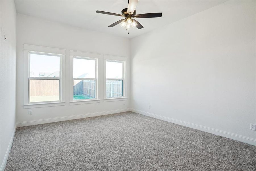 Spare room featuring carpet flooring, plenty of natural light, and ceiling fan