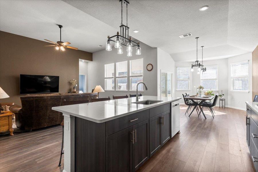 Kitchen featuring dark wood finished floors, light countertops, visible vents, a sink, and dishwasher