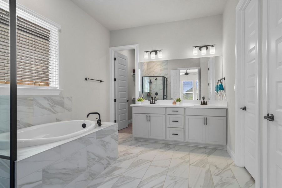Marble tiling surrounds the soaking tub and flows across the floor of this bathroom.