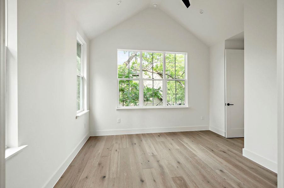 Unfurnished room with plenty of natural light, light wood-type flooring, lofted ceiling, and baseboards