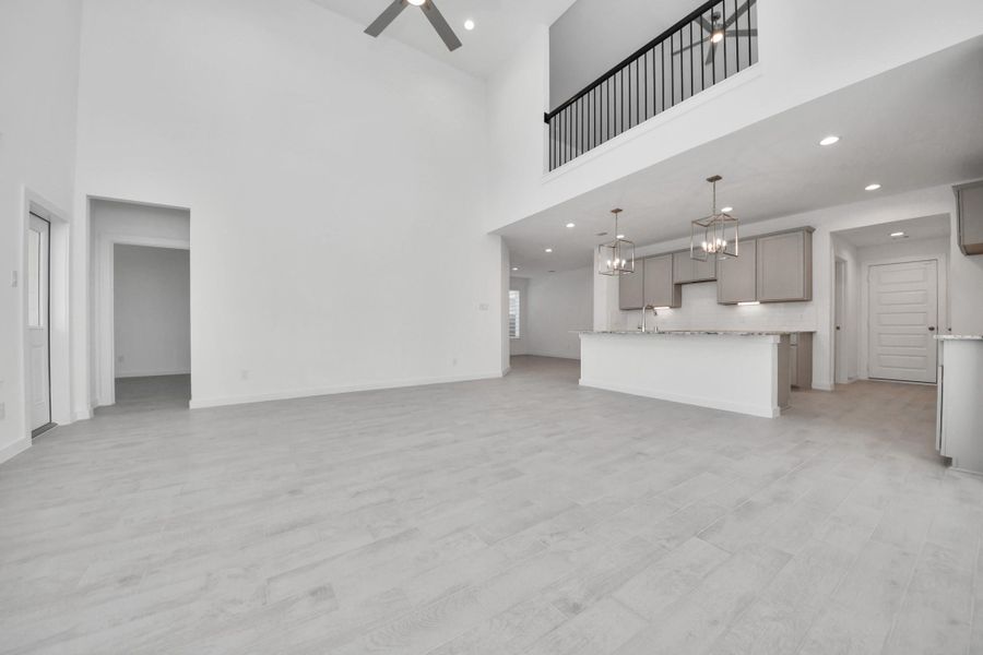 Welcome family and guests to your charming living room! With its high ceilings, recessed lighting, ceiling fan, custom paint, beautiful flooring, and large windows that let in abundant natural light, this room is perfect for gatherings. Sample photo of completed home with similar floor plan. Actual colors and selections may vary.