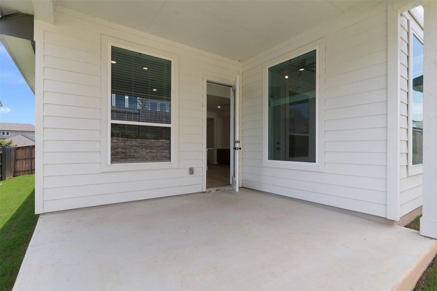 Spacious concrete patio with white horizontal siding and a large window Spacious concrete patio with white horizontal siding and a large window