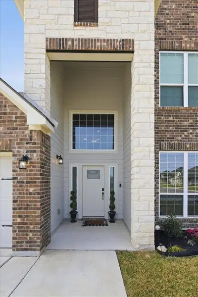 Covered property entrance featuring brick and stone siding Covered property entrance featuring brick and stone siding