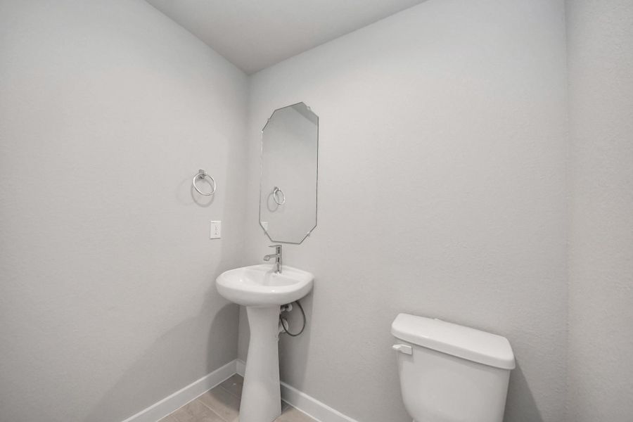 This half bathroom features a stylish pedestal sink, modern hardware, and bright recessed lighting, creating a sleek and inviting space. Sample photo of completed home with similar floor plan. Actual colors and selections may vary. This half bathroom features a stylish pedestal sink, modern hardware, and bright recessed lighting, creating a sleek and inviting space. Sample photo of completed home with similar floor plan. Actual colors and selections may vary.