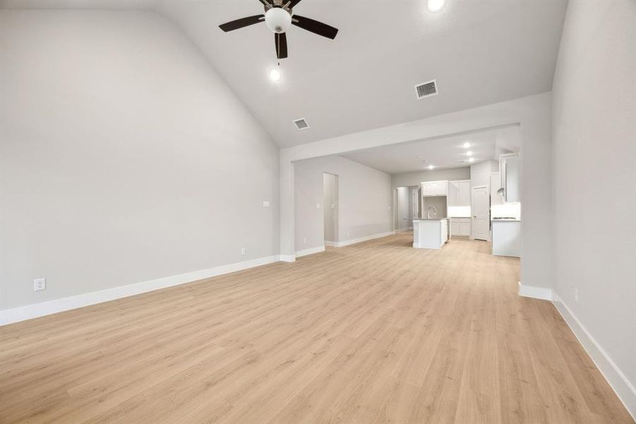 Unfurnished living room featuring lofted ceiling, ceiling fan, and light hardwood / wood-style flooring