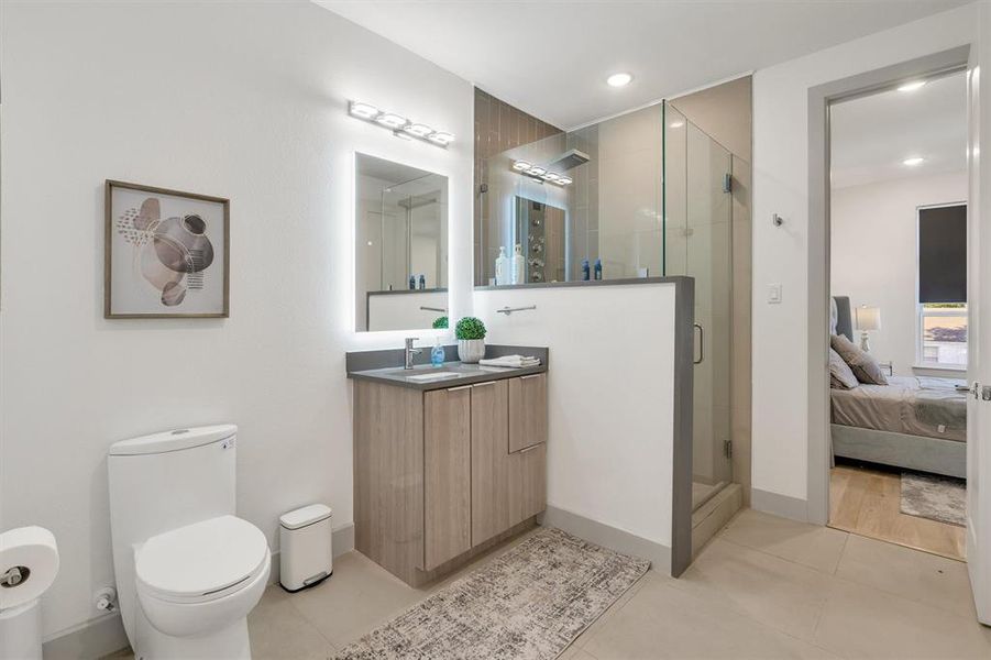 Bathroom with toilet, vanity, tile patterned floors, and a shower with shower door