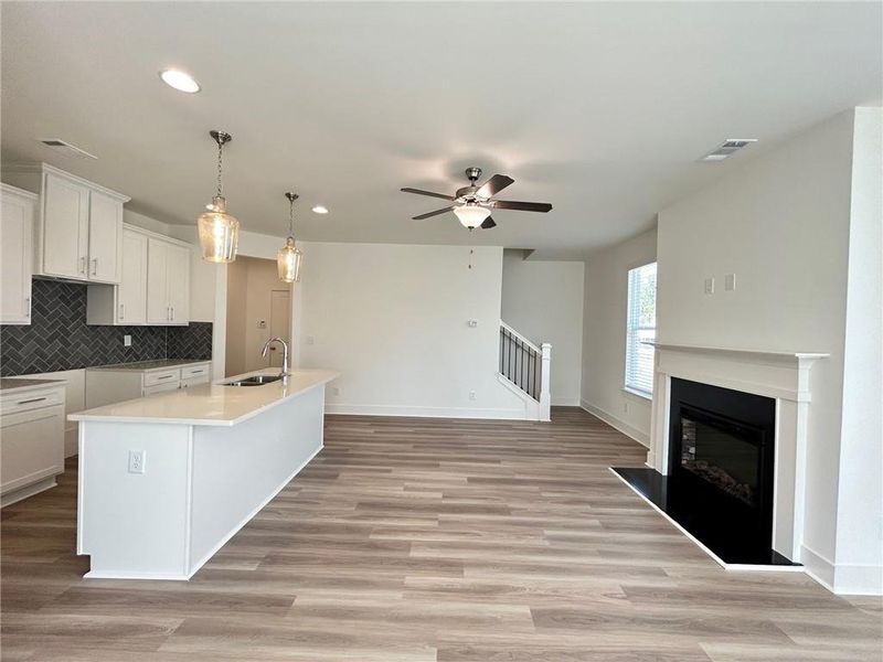 Kitchen featuring ceiling fan, a center island with sink, hanging light fixtures, and tasteful backsplash