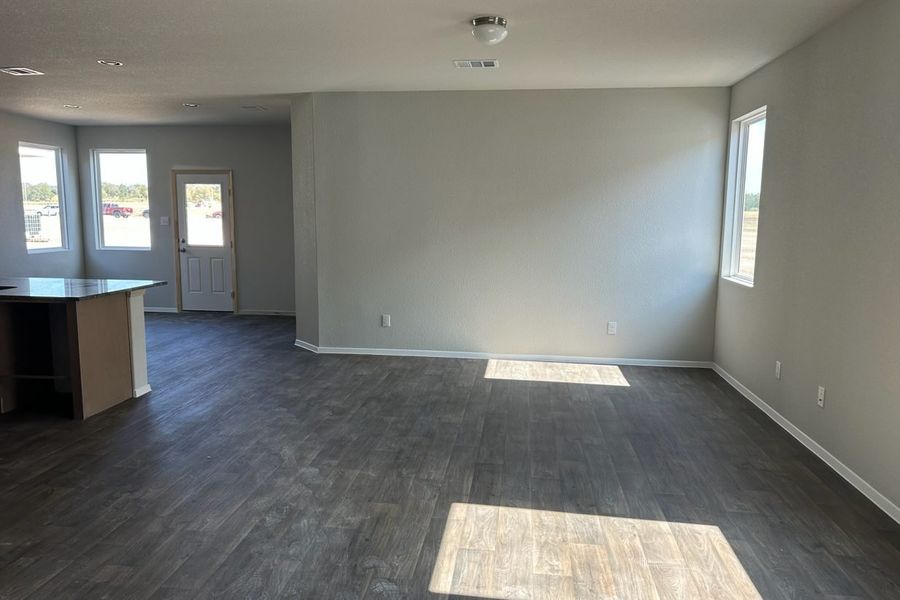 Image of home living and dining areas with wood-look floors, white walls, and windows