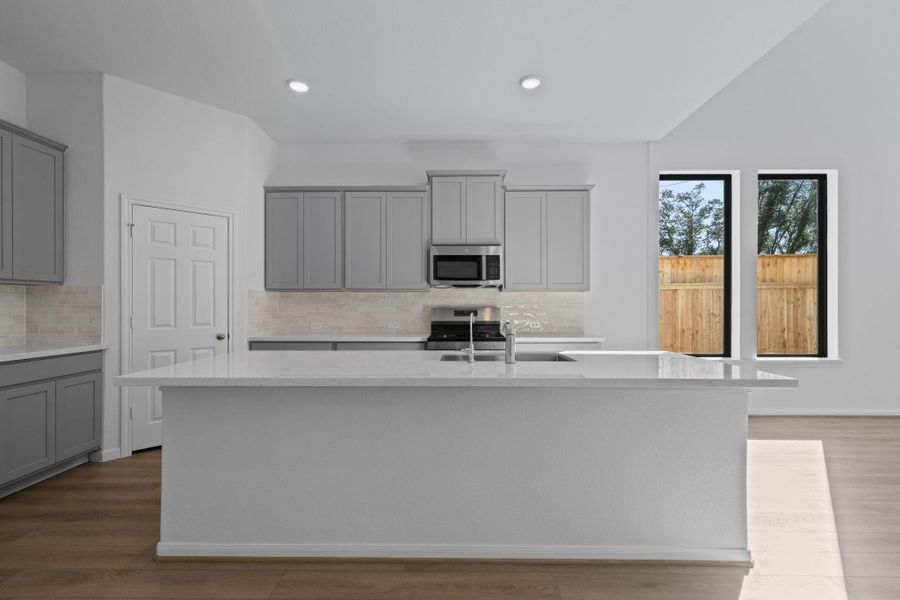 This light and bright kitchen features a large quartz island, white cabinets, a large sink overlooking your family room, recessed lighting, and beautiful backsplash. This light and bright kitchen features a large quartz island, white cabinets, a large sink overlooking your family room, recessed lighting, and beautiful backsplash.