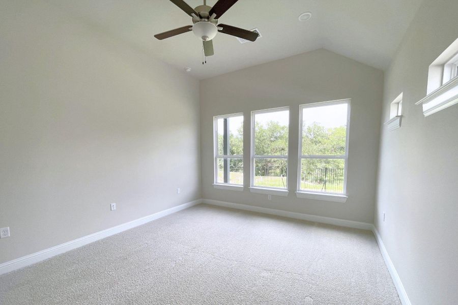A quiet bedroom retreat with soaring ceilings and verdant views from large, naturally illuminated windows.
