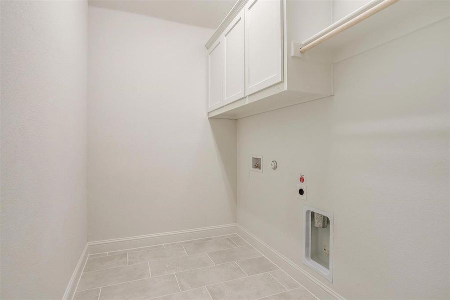 Washroom with washer hookup, cabinets, light tile patterned floors, and hookup for an electric dryer