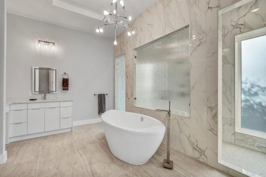 Bathroom with vanity, a freestanding tub, a chandelier, a marble finish shower, and healthy amount of natural light