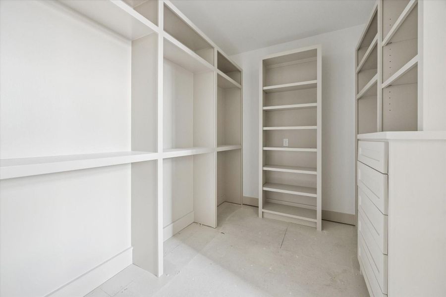 PRIMARY CLOSET - Custom walk in closet is fully built out with open shelving, hanging space, and integrated drawers, offering thoughtful organization from top to bottom. Neutral finishes and generous proportions create a boutique style storage experience designed to adapt as needs evolve. -- Construction as of 1/5/26