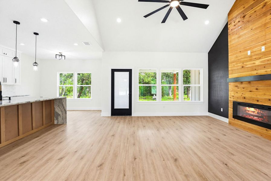 A striking fireplace with rich wood accents complements the natural light filling this spacious, open-concept living area.