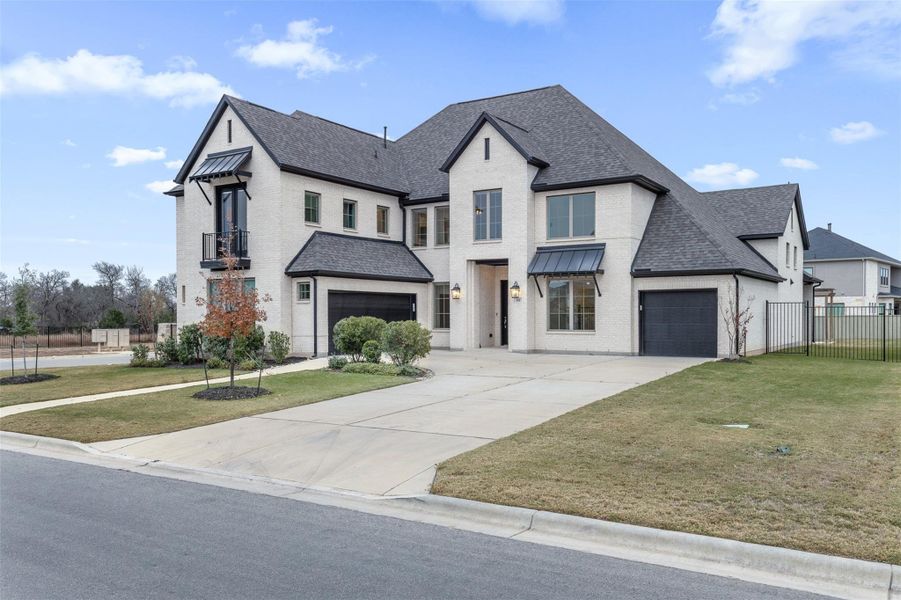 View of front of house featuring a shingled roof, a standing seam roof, brick siding, driveway, and a metal roof