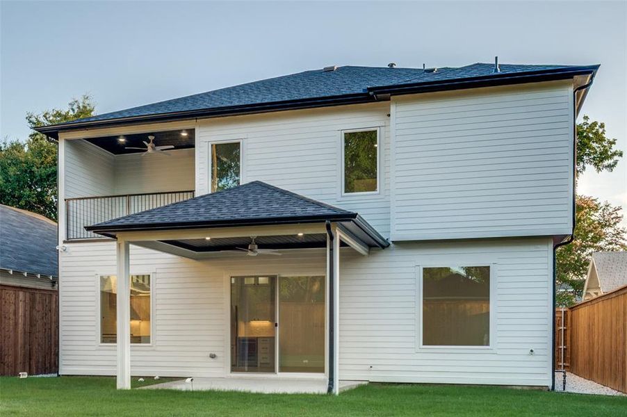 Rear view of house with a ceiling fan, a balcony, and roof with shingles