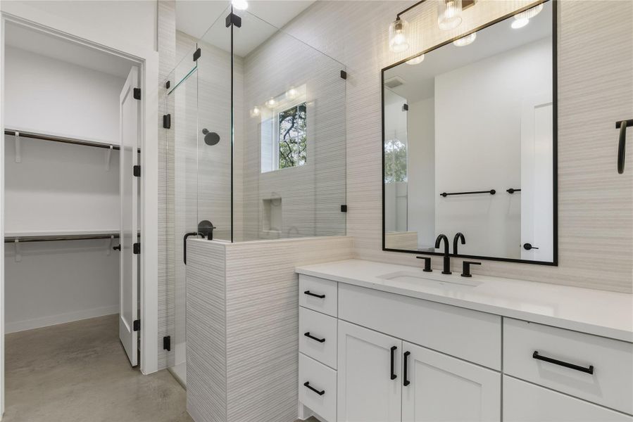 Full bathroom junior suite with vanity, a stall shower, finished concrete floors, and a walk in closet Full bathroom junior suite with vanity, a stall shower, finished concrete floors, and a walk in closet