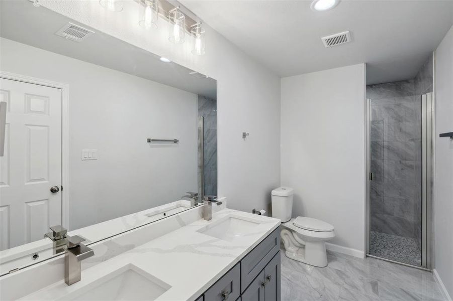 Bathroom featuring vanity, toilet, and a shower with shower door