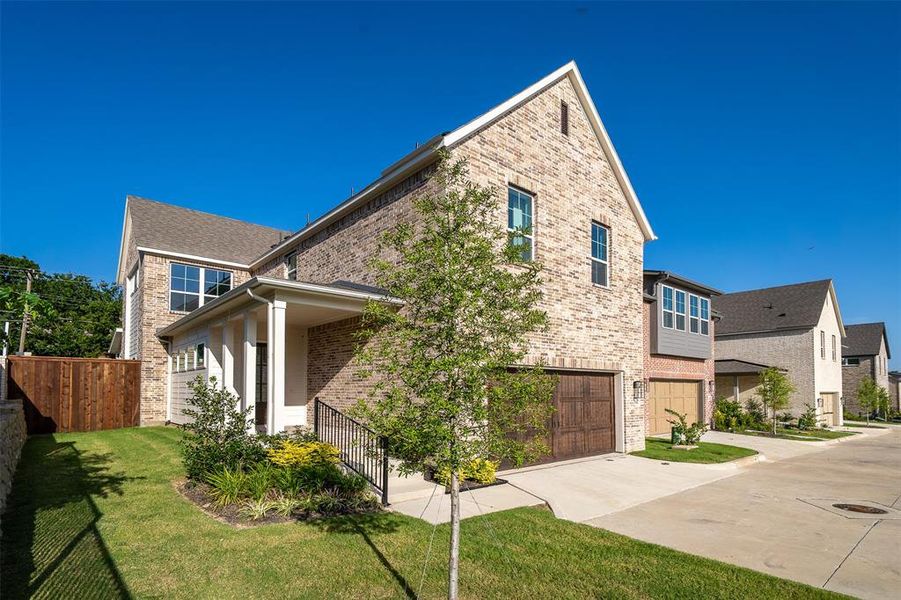 Contemporary multi-story residence featuring light-toned brick facade, gabled roofline, and a wood-finish garage door Contemporary multi-story residence featuring light-toned brick facade, gabled roofline, and a wood-finish garage door