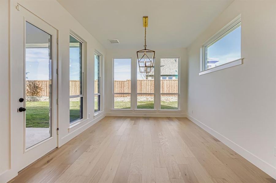 Unfurnished sunroom featuring wood finished floors and a chandelier