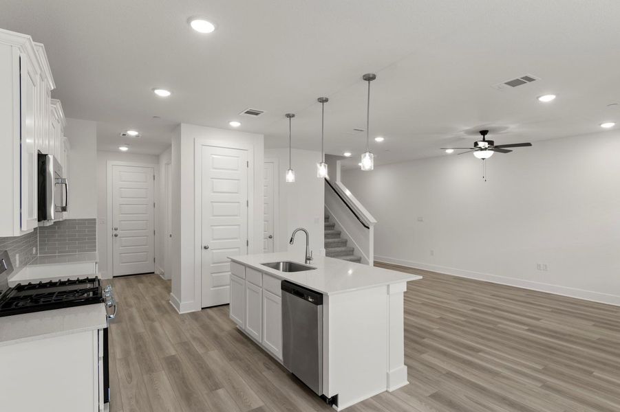 Kitchen with appliances with stainless steel finishes, white cabinetry, pendant lighting, an island with sink, and decorative backsplash