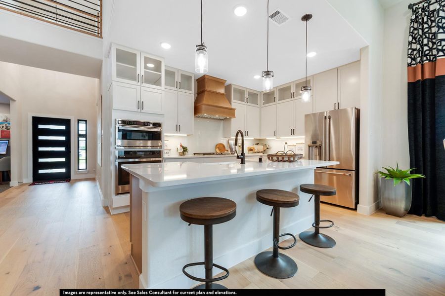 Kitchen featuring light wood-style flooring, stainless steel appliances, pendant lighting, a kitchen breakfast bar, and an island with sink Kitchen featuring light wood-style flooring, stainless steel appliances, pendant lighting, a kitchen breakfast bar, and an island with sink