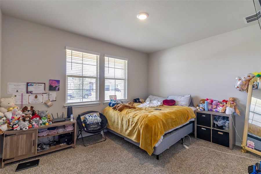 Well-lit and comfortable, this bedroom features carpet flooring and practical blinds on its windows.