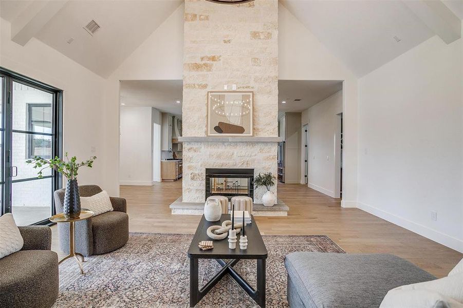 Living room with light hardwood / wood-style floors, high vaulted ceiling, and a fireplace