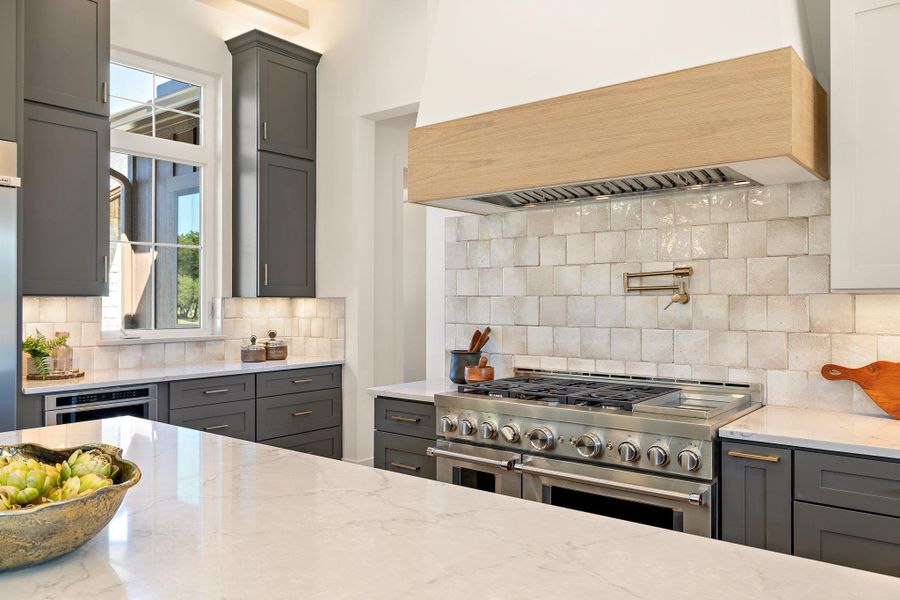 Kitchen featuring gray cabinetry, appliances with stainless steel finishes, and custom range hood