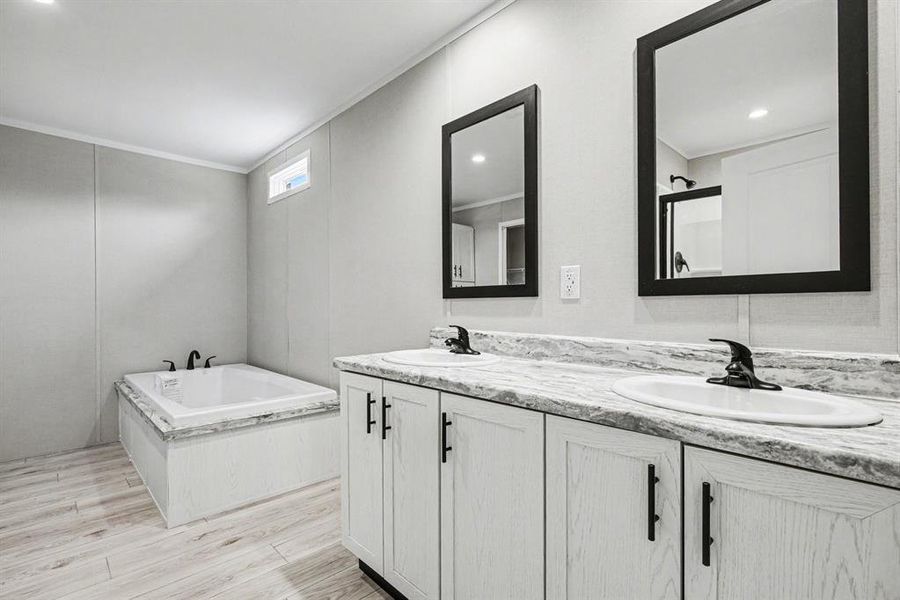 Primary bathroom featuring a luxury soaker tub, double vanity with white cabinetry, dual black framed mirrors, integrated china sinks, and black fixtures - so many upgardes!