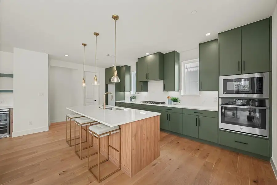 Contemporary kitchen featuring a large central island with seating, a white countertop, and a built-in sink Contemporary kitchen featuring a large central island with seating, a white countertop, and a built-in sink