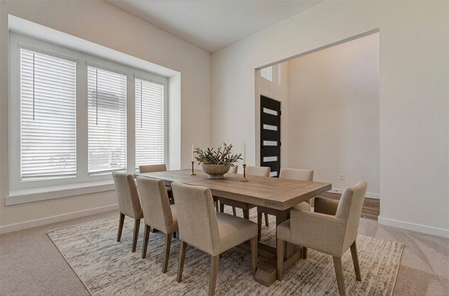 This spacious front dining area is filled with natural light from large windows, creating an airy and comfortable environment. Perfect for relaxing or entertaining, the room offers flexible use and seamlessly connects to the entryway. The soft carpet underfoot and neutral palette provide a blank canvas, allowing future homeowners to easily personalize the space to suit their lifestyle. This photo is virtually staged.
