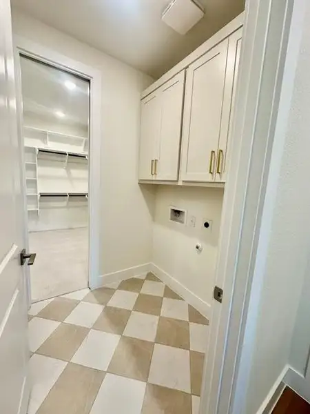 Functional laundry space boasts convenient upper cabinetry, seamlessly connecting to a large walk-in closet.
