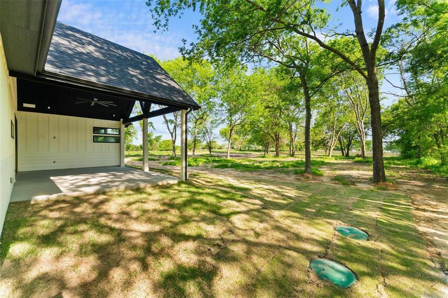 View of green lawn featuring ceiling fan and a patio area View of green lawn featuring ceiling fan and a patio area