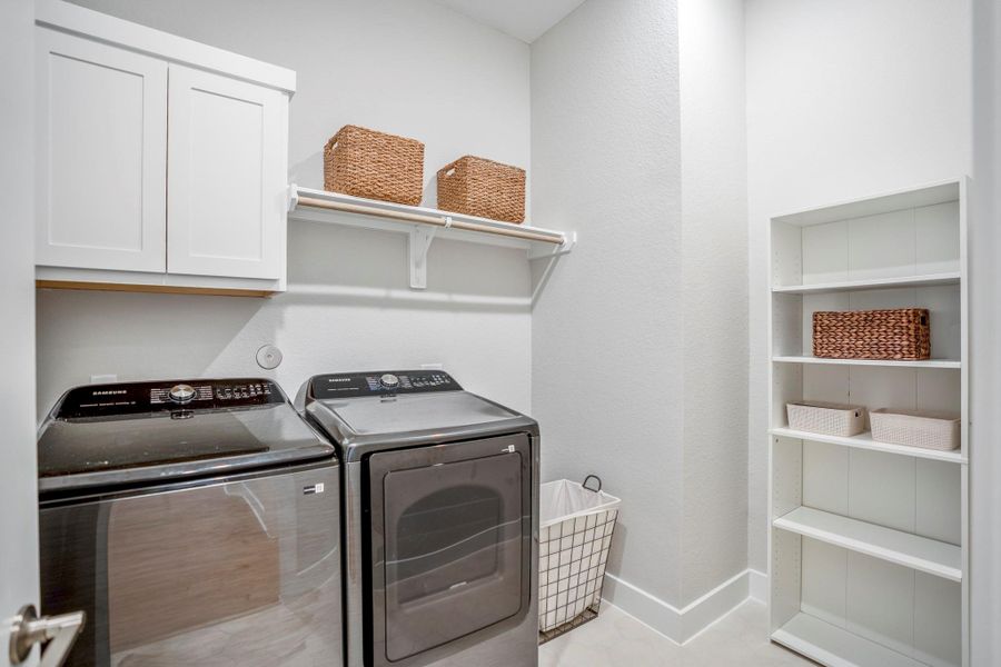 This roomy utility room keeps laundry day organized with built-in cabinetry, open shelving and connections for either a gas or electric dryer.
