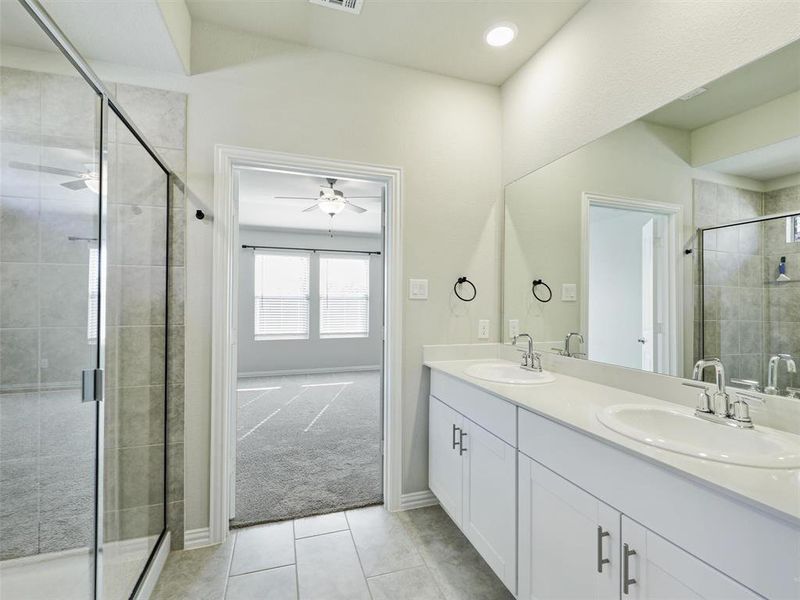 Bathroom featuring tile patterned flooring, vanity, ceiling fan, and a shower with door