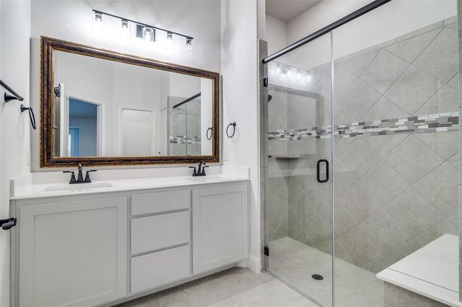 Ensuite bathroom featuring vanity, dual sinks, tile patterned floors, and a huge walk in shower