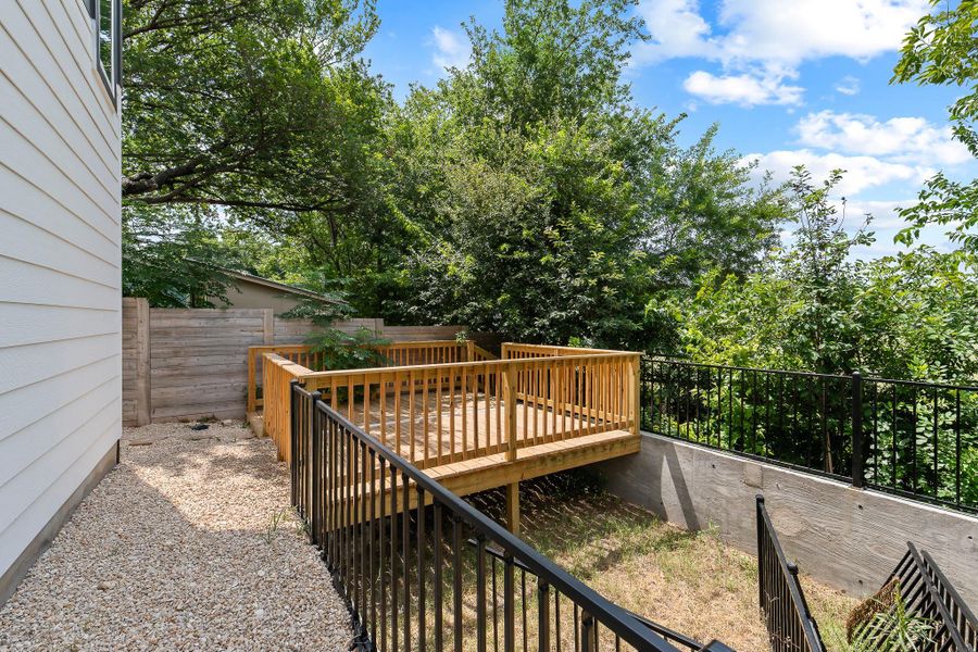 A spacious wooden deck extends into a lush, green yard, offering a peaceful outdoor retreat.