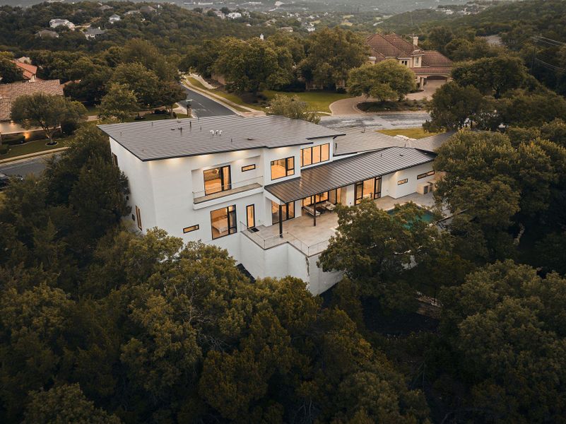 An aerial perspective showcases a modern dwelling nestled amongst verdant trees, featuring multiple balconies and expansive windows. An aerial perspective showcases a modern dwelling nestled amongst verdant trees, featuring multiple balconies and expansive windows.