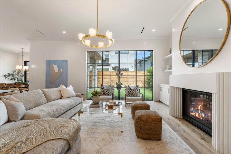 The luxe living room, featuring 11-foot ceilings, showcases a gas log fireplace flanked with custom cast stone surround and mantle and custom. Sprawling windows flood the space with natural light—which bounces off the Venetian plaster walls.