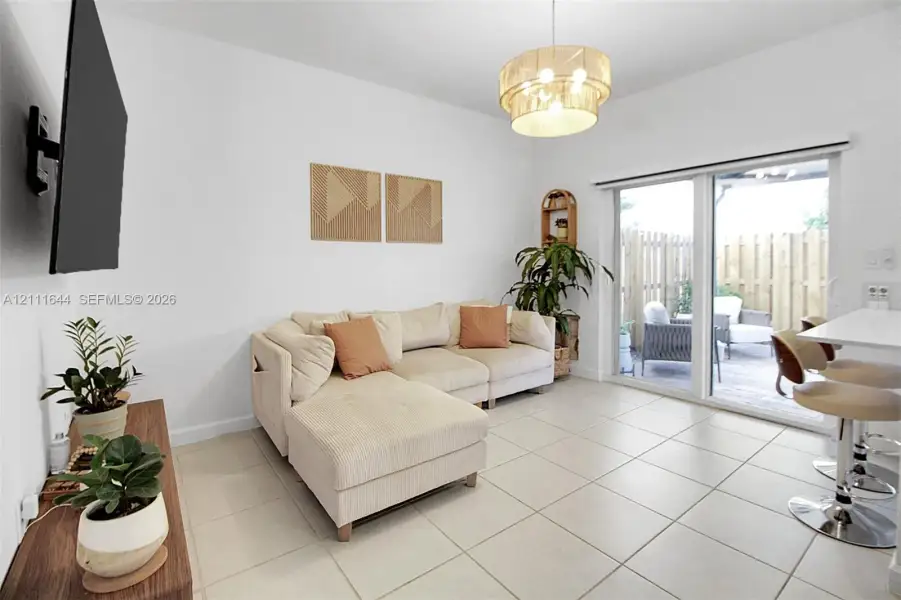 Neutral tile flooring, tiered drum pendant lighting, and a large sliding glass door featuring integrated patio access Neutral tile flooring, tiered drum pendant lighting, and a large sliding glass door featuring integrated patio access