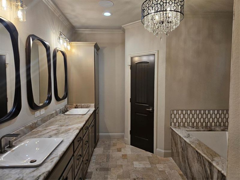 Bathroom featuring a relaxing tiled tub, vanity, and crown molding