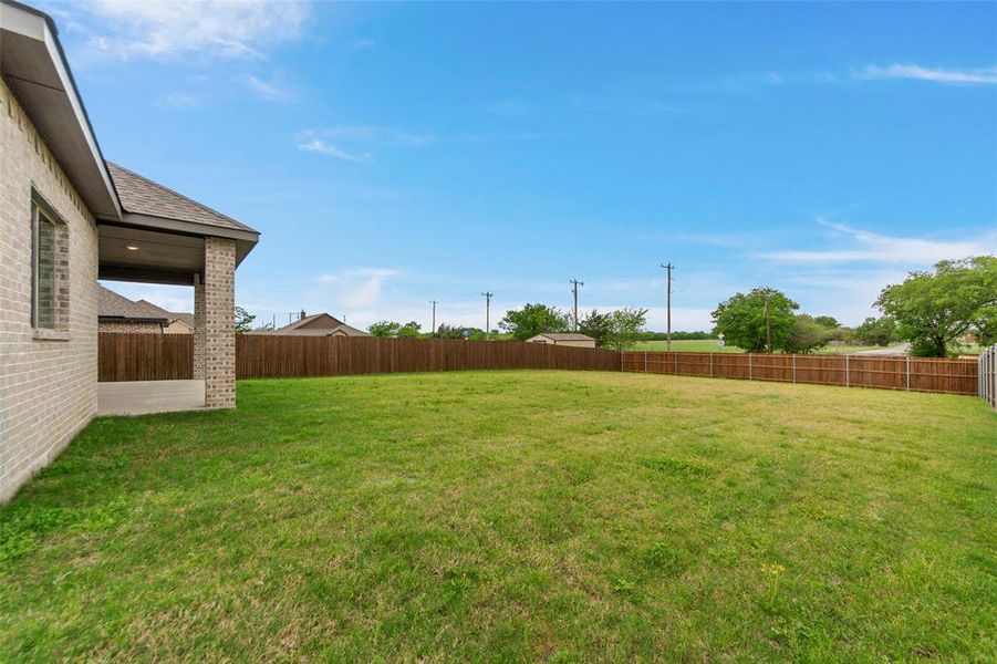 Expansive backyard featuring a manicured lawn and a privacy fence