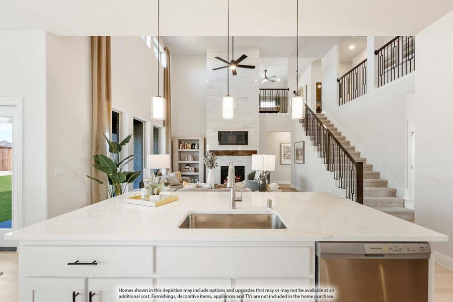 Kitchen island with quartz countertop and sink overlooking open living room with two-story ceiling and staircase