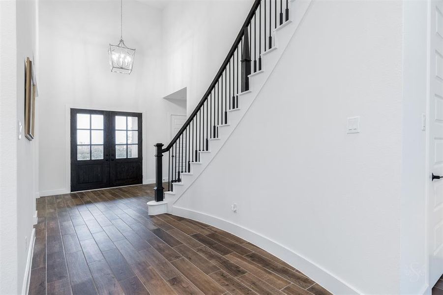 Stunning two-story light-washed entry highlights wood like tile and dramatic sweeping staircase with designer spindles.