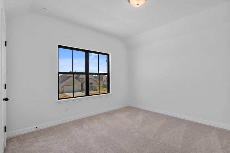 An inviting secondary bedroom that feels elevated yet effortlessly livable with plush carpet and large windows.